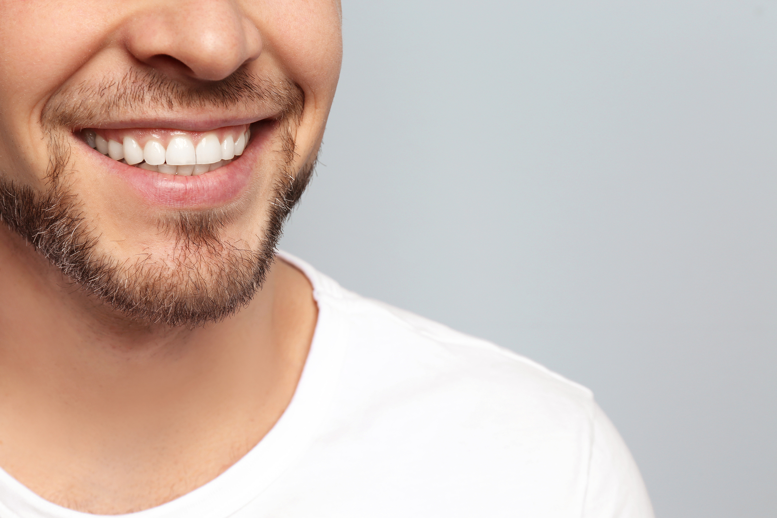 Young Man With Beautiful Smile On Grey Background